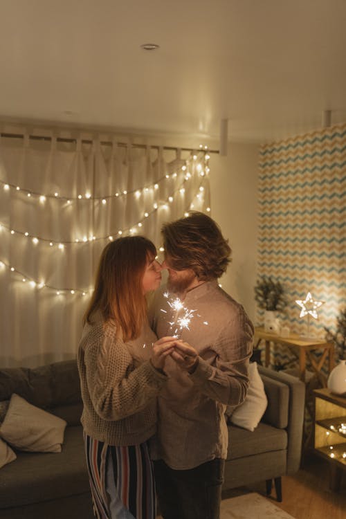 A Couple Looking at Each Other while Holding a Burning Sparklers