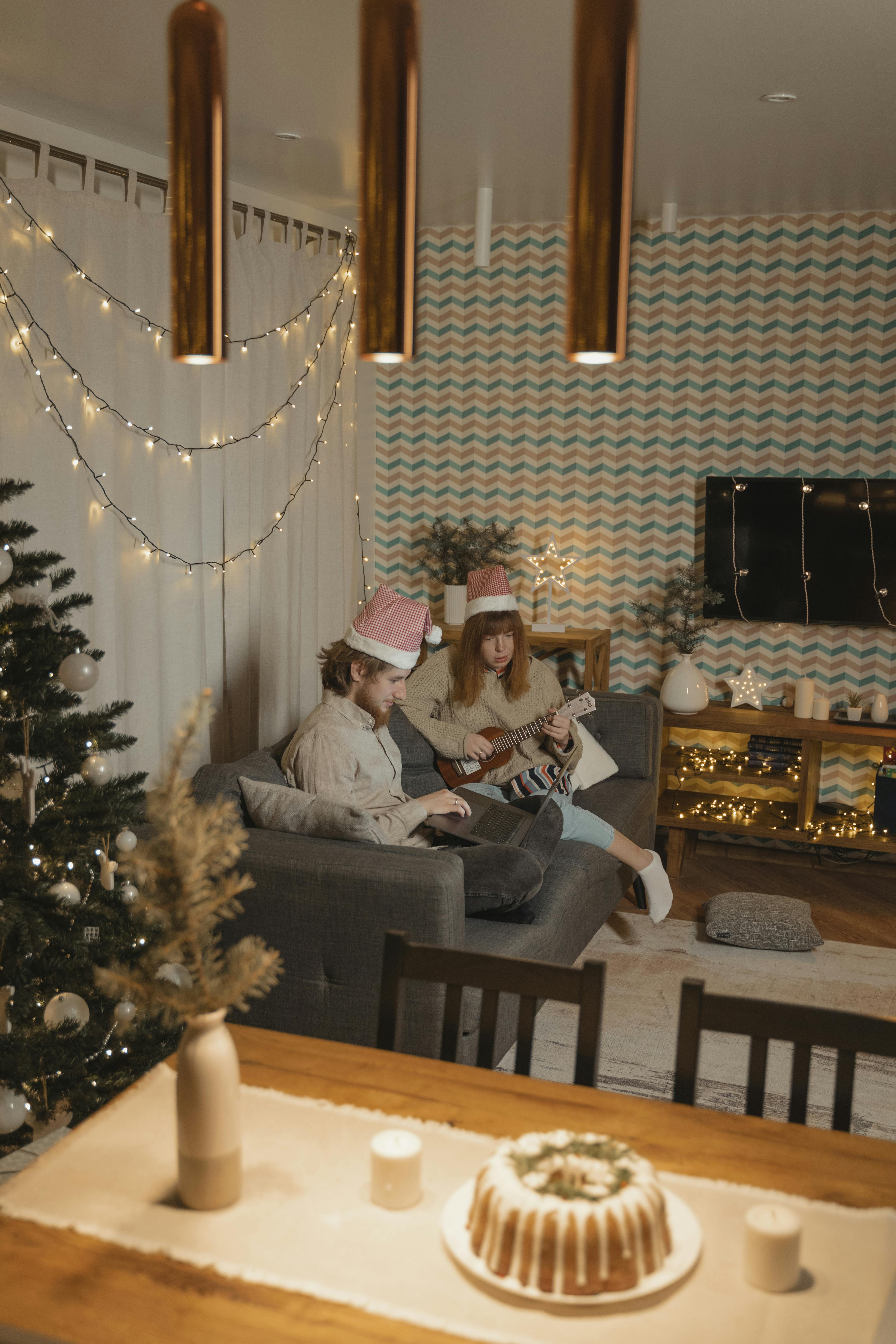 man and woman sitting on couch with santa hats