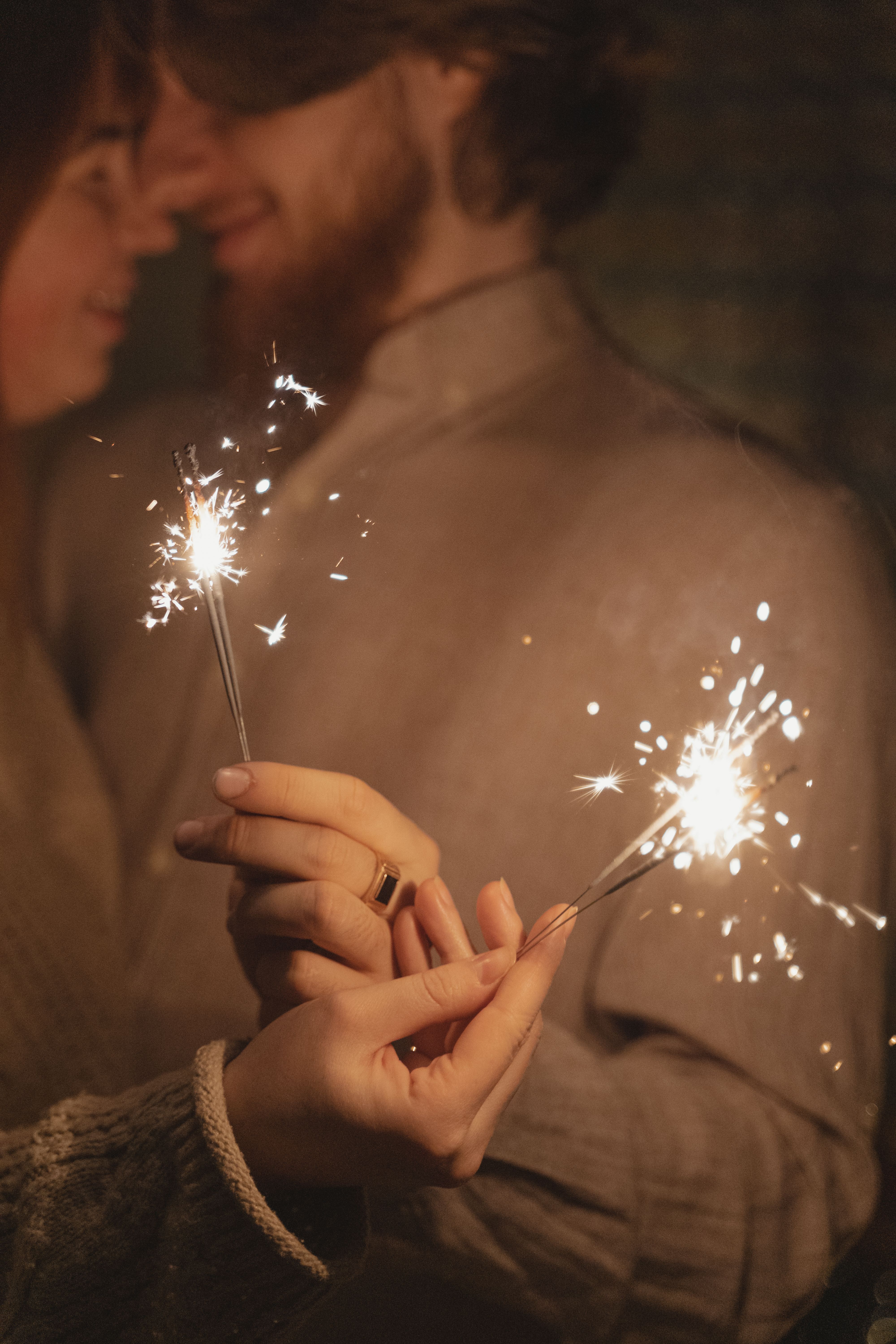 一对快乐的夫妇在室内拿着烟花，享受浪漫庆祝活动的特写镜头
