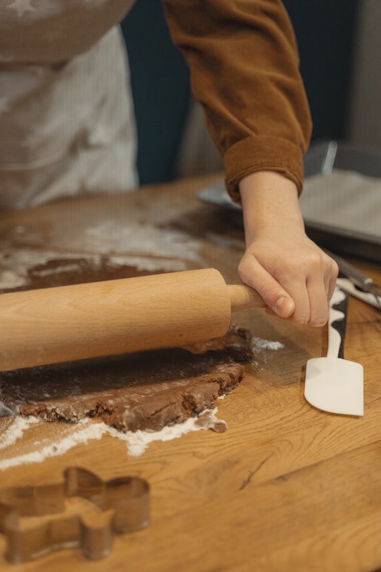 Hand Holding Brown Wooden Rolling Pin