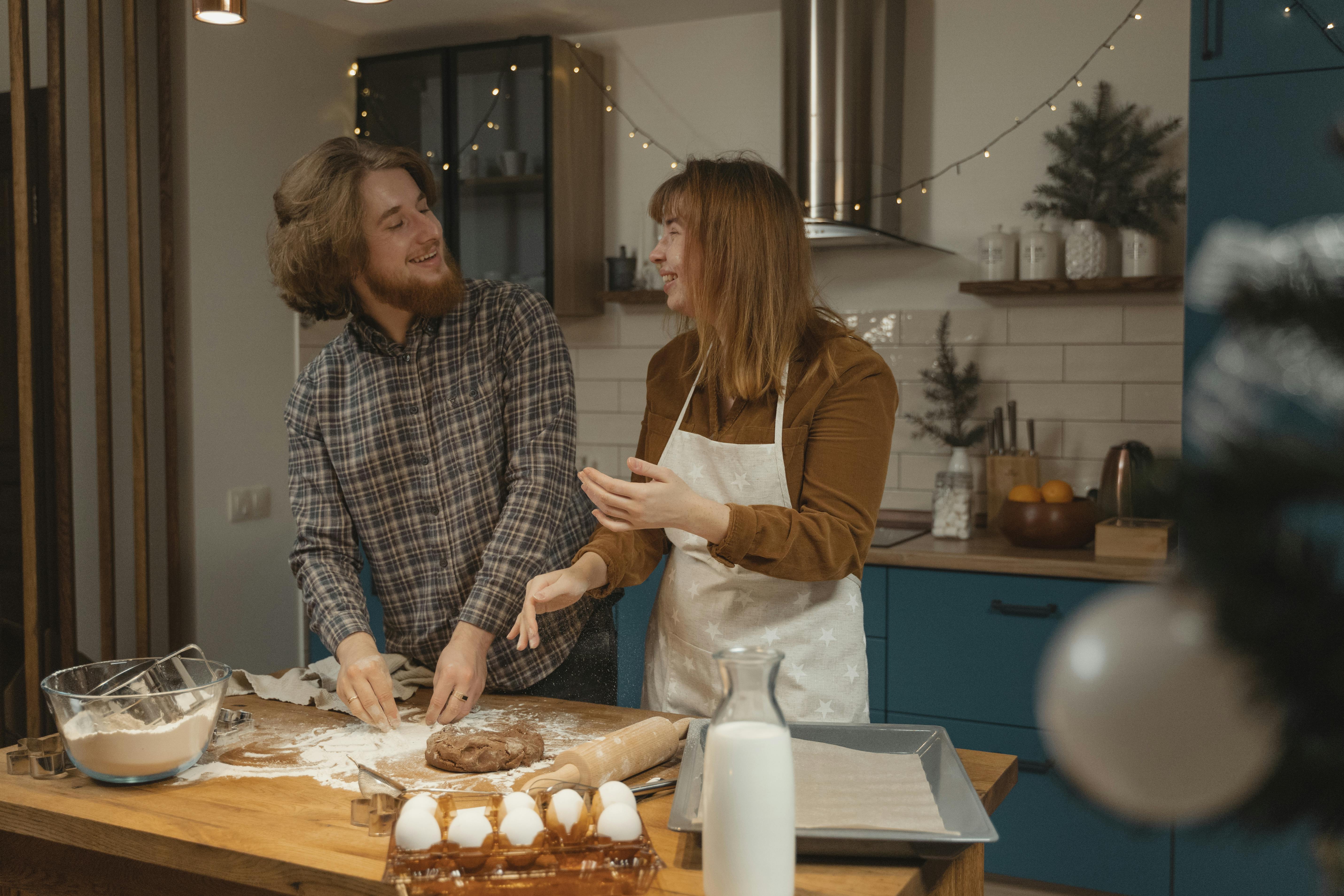 happy couple standing at the table with flour and dough