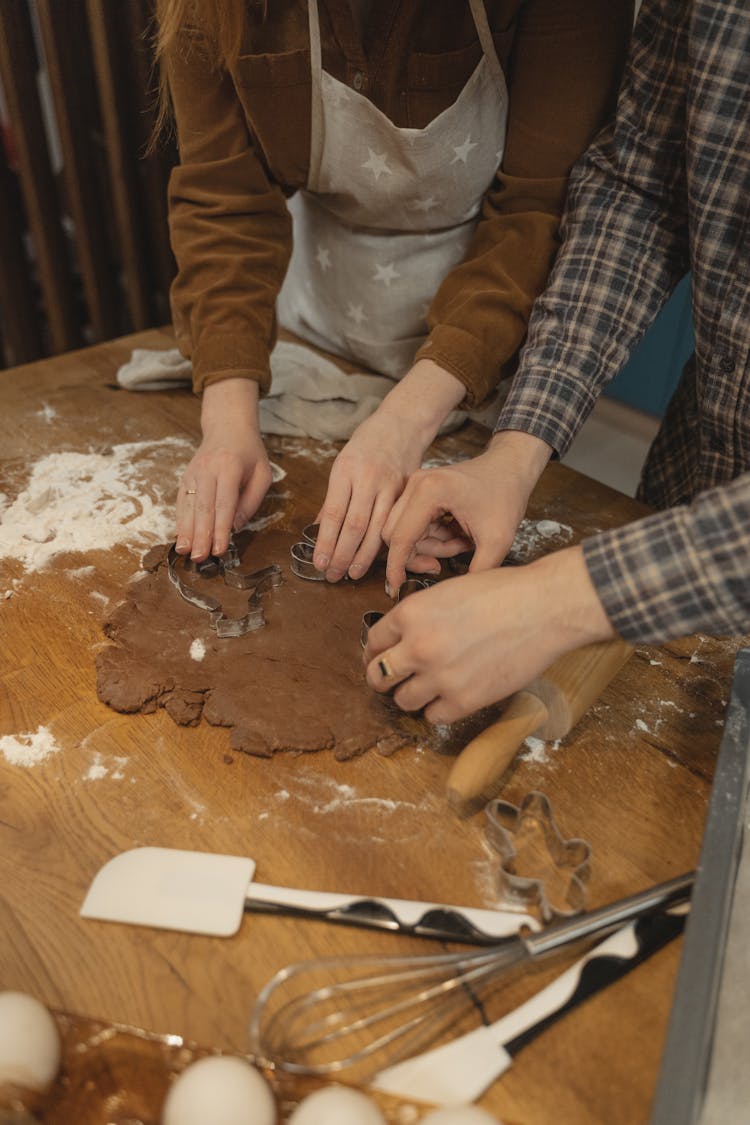 Two People Using Cookie Cutter On Chocolate Dough