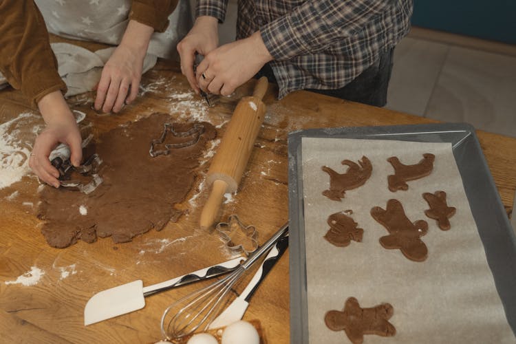 Two People Using Cookie Cutter On Chocolate Dough