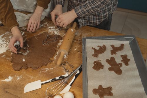 Free Two people bake different shaped cookies using chocolate dough on a wooden table. Stock Photo