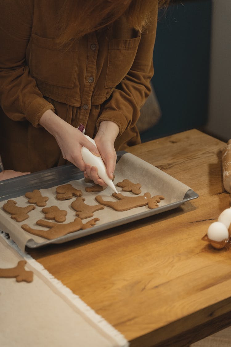 Person Frosting Brown Dough With Piping Bag