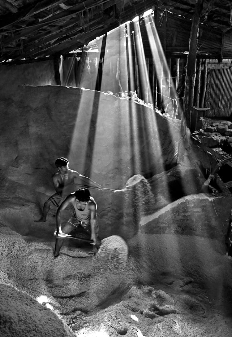 Grayscale Photo Of Men Shoveling Salt 