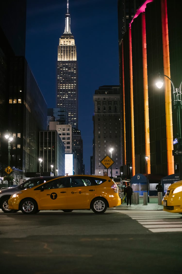 Contemporary Cars Riding On Night City Street Near Illuminated Skyscrapers