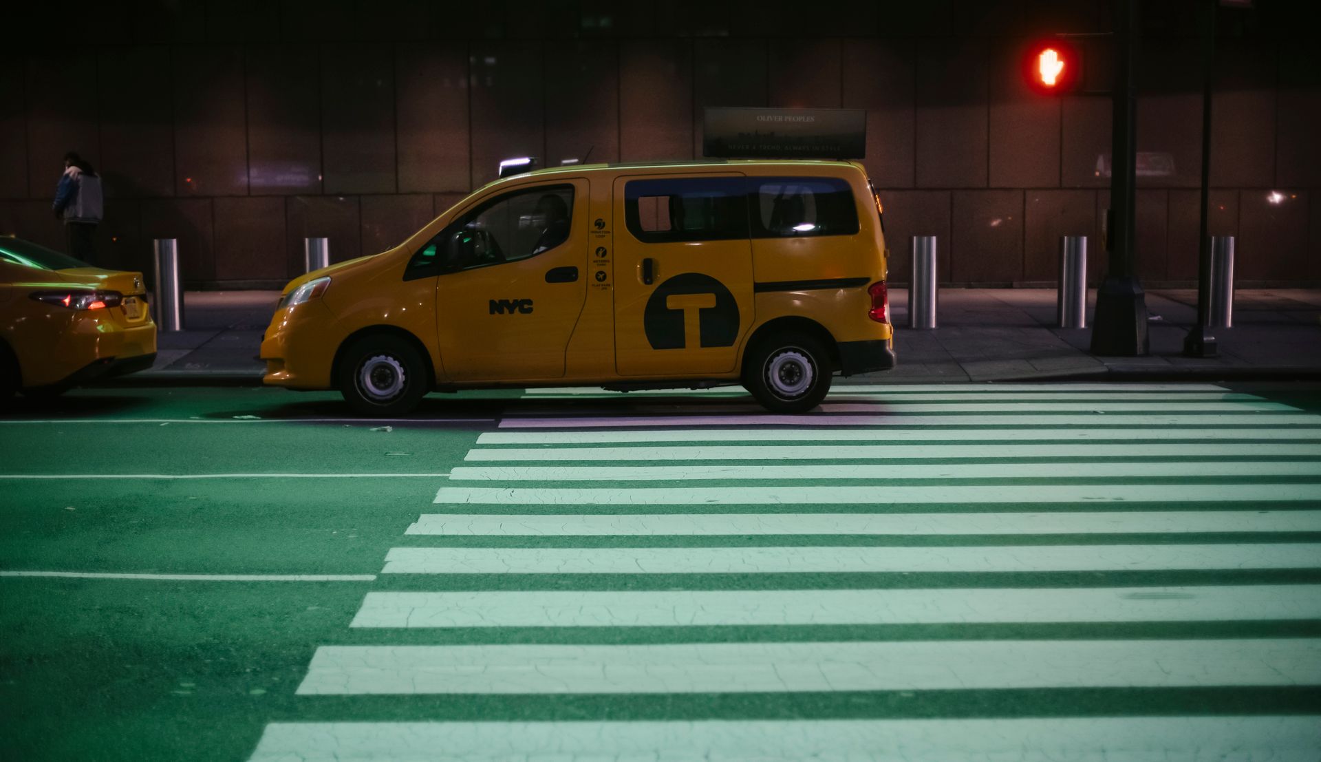 Comfortable yellow minivan cab parked on city asphalt road near traffic light at night