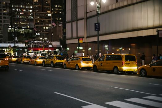 纽约市的街道上，夜间停着一排标志性的黄色出租车