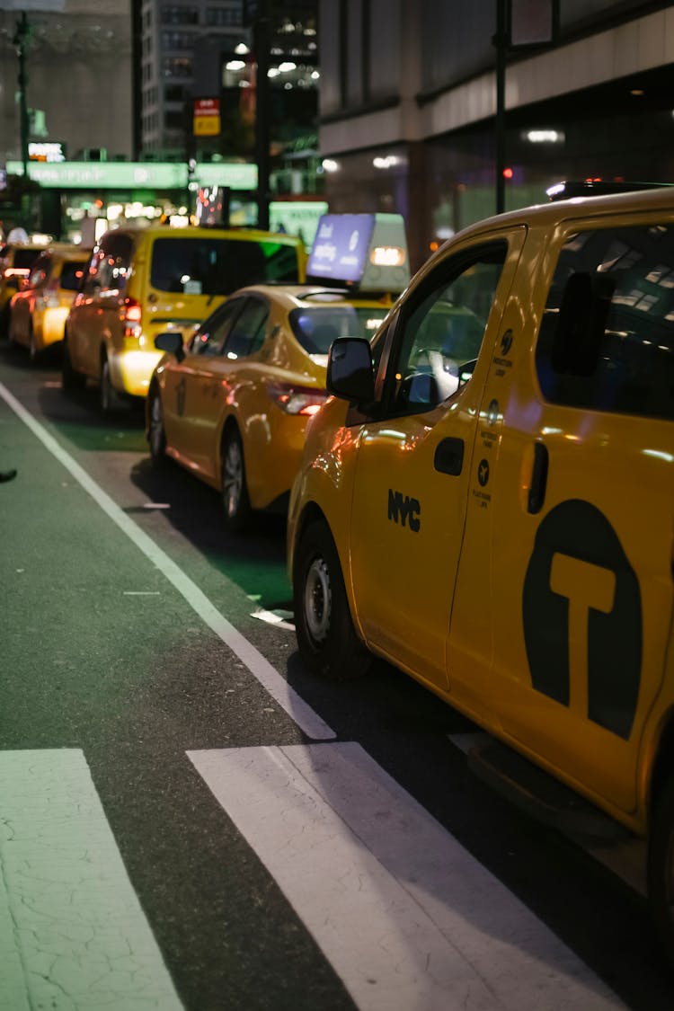 Shiny Yellow Taxi Cars In Street Parking At Night