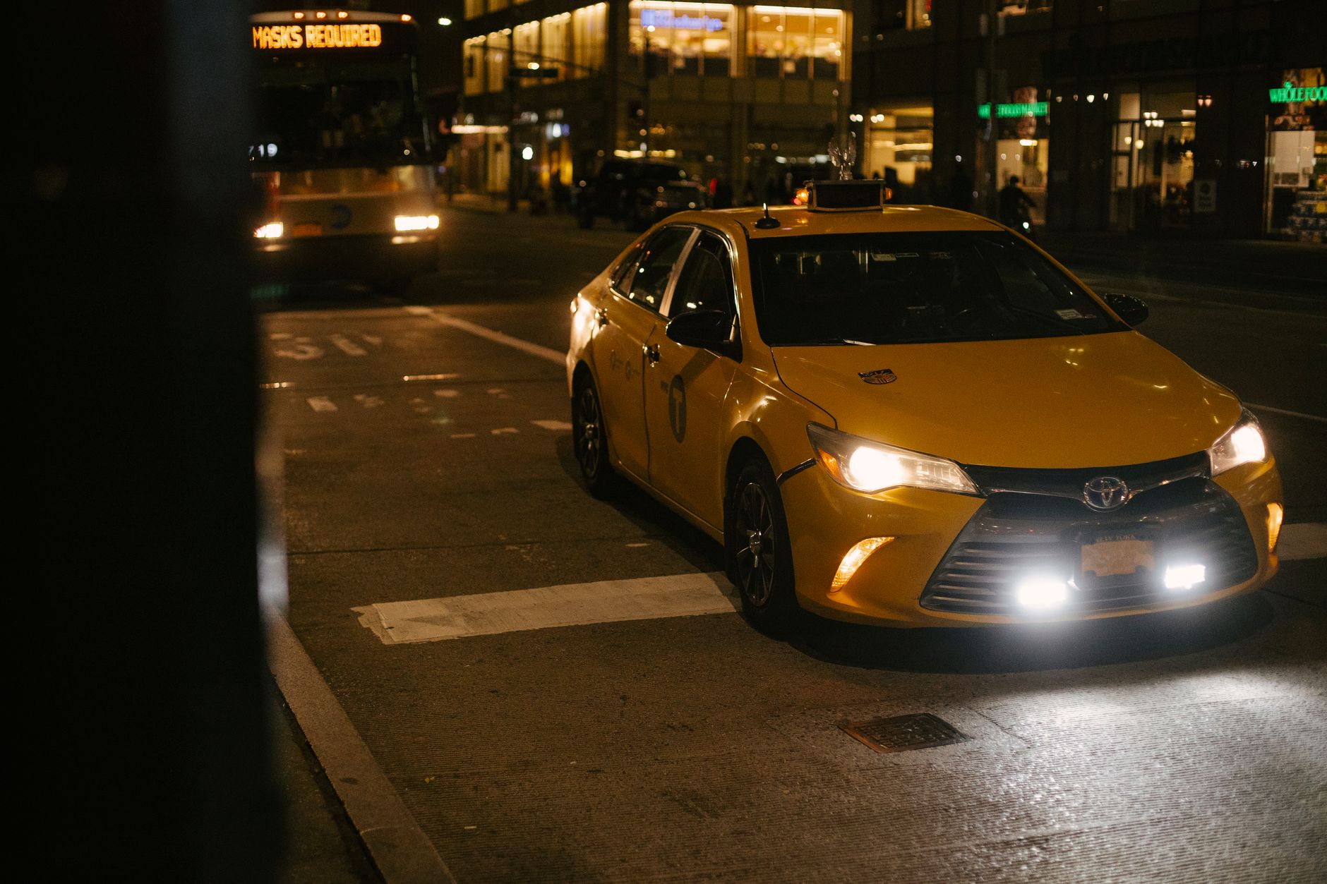 Night city street view with yellow cabs and glowing neon lights after an event