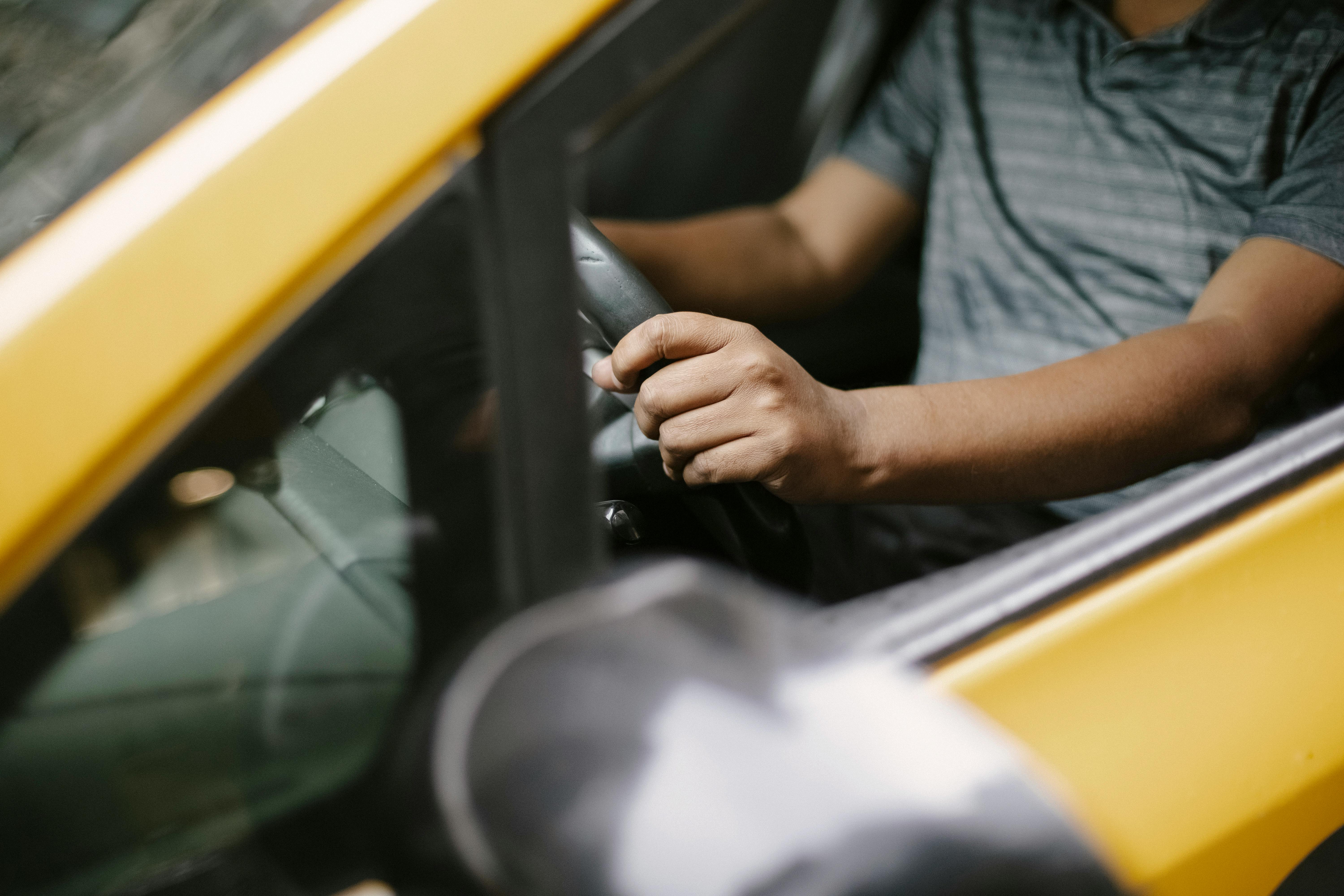 Crop casual man driving taxi in city
