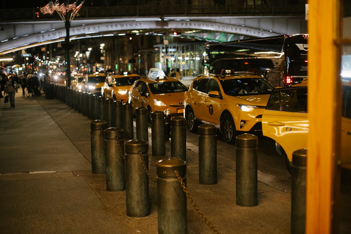 Free Row of modern shiny yellow taxis with glowing headlights parked at roadside near Grand Central Terminal in New York at night Stock Photo