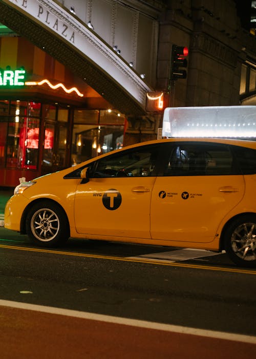 夜のネオンサインと建物の近くの都市道路上のミニバンタクシー車