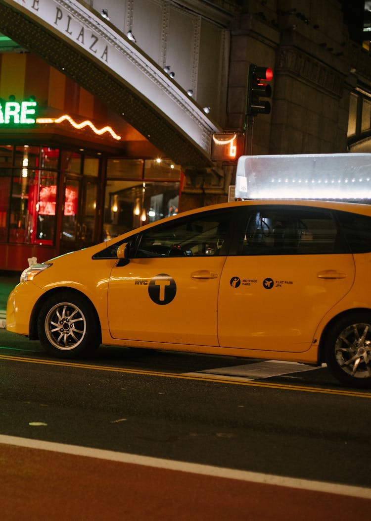 Minivan Taxi Car On City Road Near Building With Neon Sign At Night