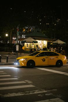 深夜，一辆黄色出租车驶过灯光昏暗、城市灯火模糊的街道