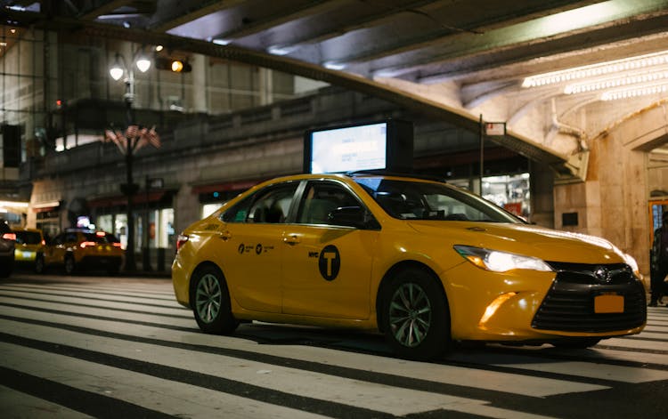 Shiny Fashioned Taxi With Glowing Headlights Driving On Road At Night