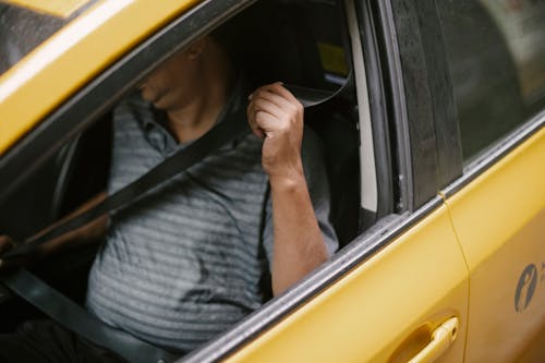 Free Unrecognizable male driver sitting in cab and fastening seat belt Stock Photo
