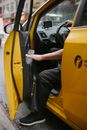 Crop anonymous male opening door of bright yellow car parked on asphalt road on local street of town