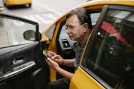 Thoughtful ethnic man touch screen of smartphone in car