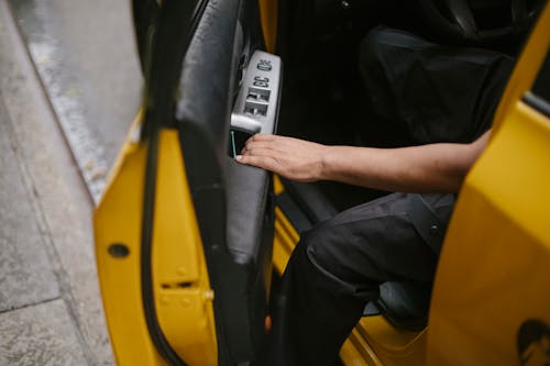 Unrecognizable man getting out of yellow car