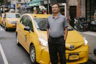 Tranquil man in glasses standing with hands in pockets against yellow cars on street in city in daytime