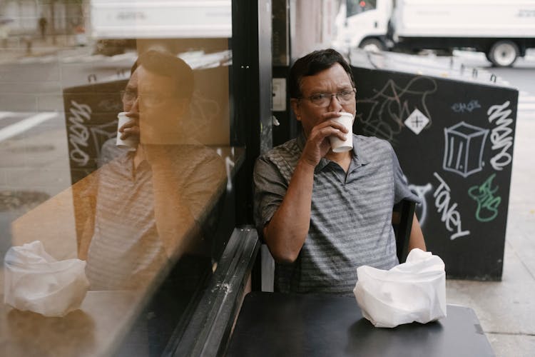 Thoughtful Ethnic Man Drinking Coffee In Street Cafe