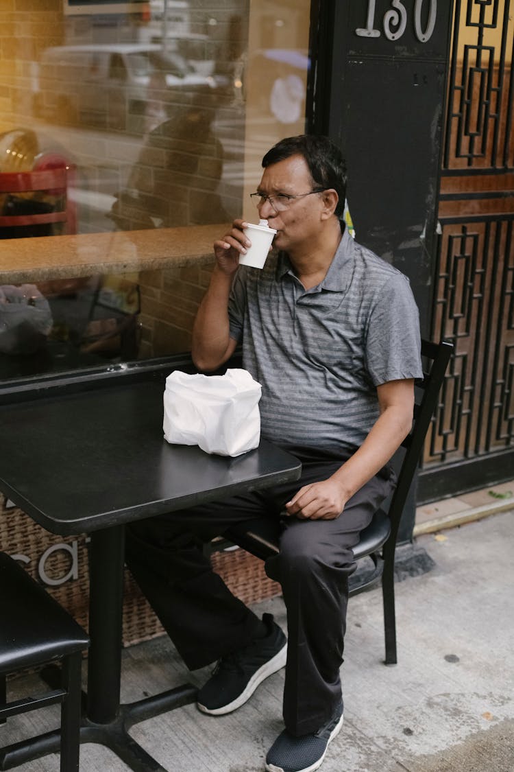 Ethnic Man Sipping Coffee In Street