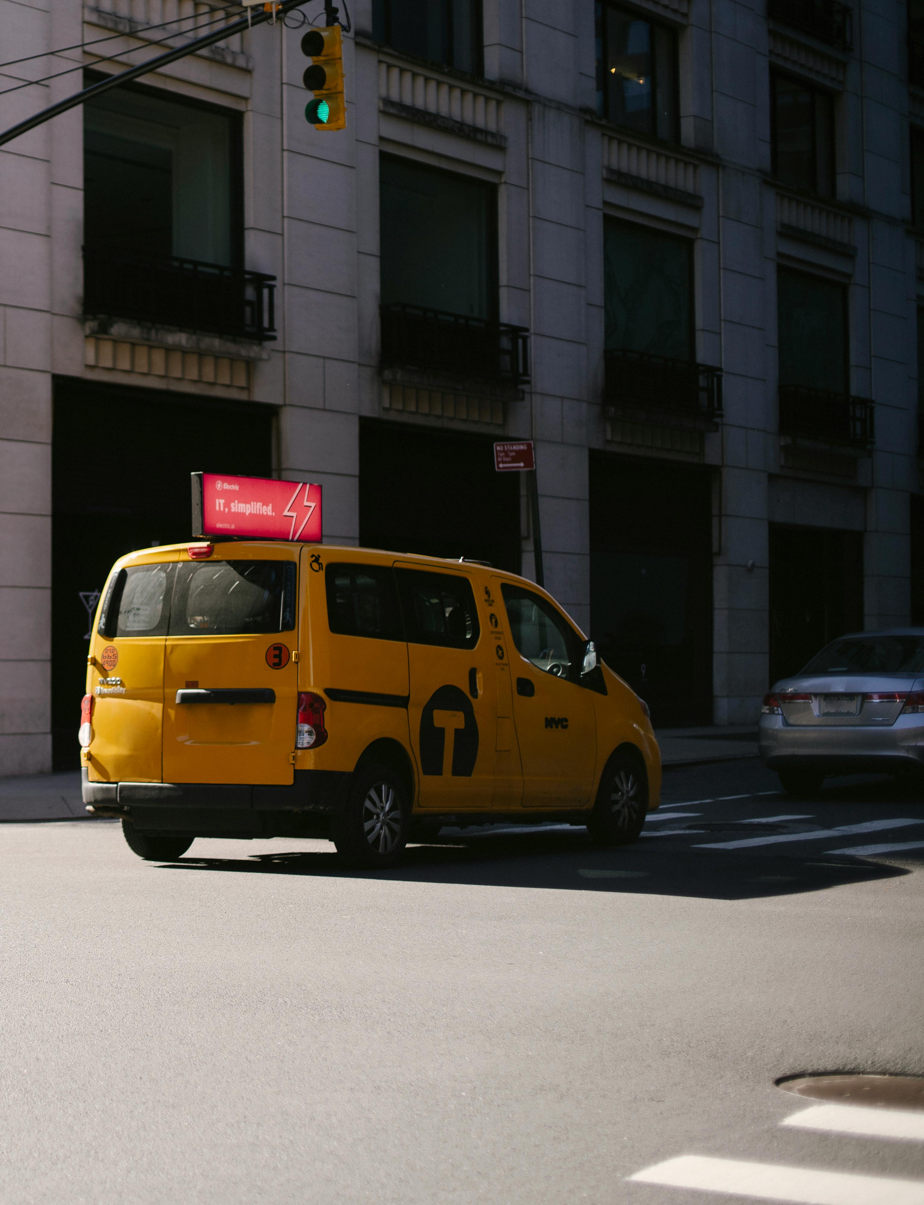 yellow taxi riding on road