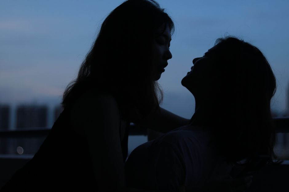 Silhouette of a romantic lesbian couple sharing an intimate moment at dusk in Singapore.