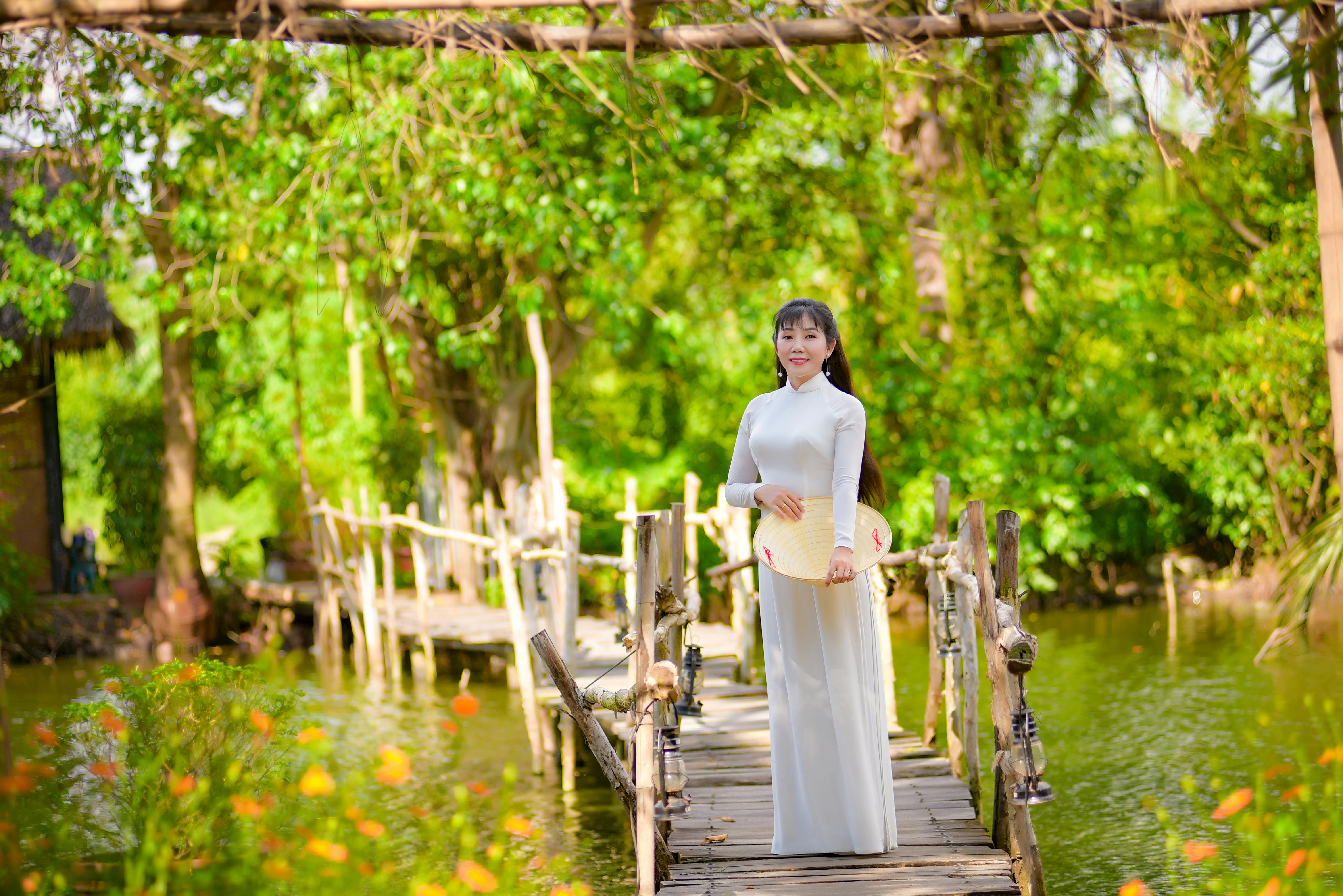 woman in white dress standing on a wooden pathway in a lake