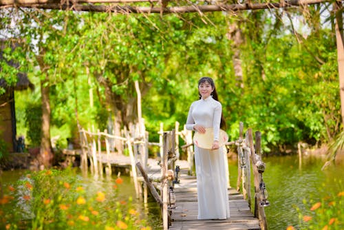 Free Woman in White Dress Standing on a Wooden Pathway in a Lake Stock Photo