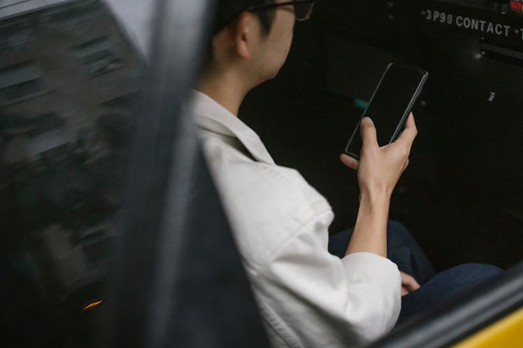 High Angle Of Taxi Passenger Using Smartphone While Sitting On Backseat