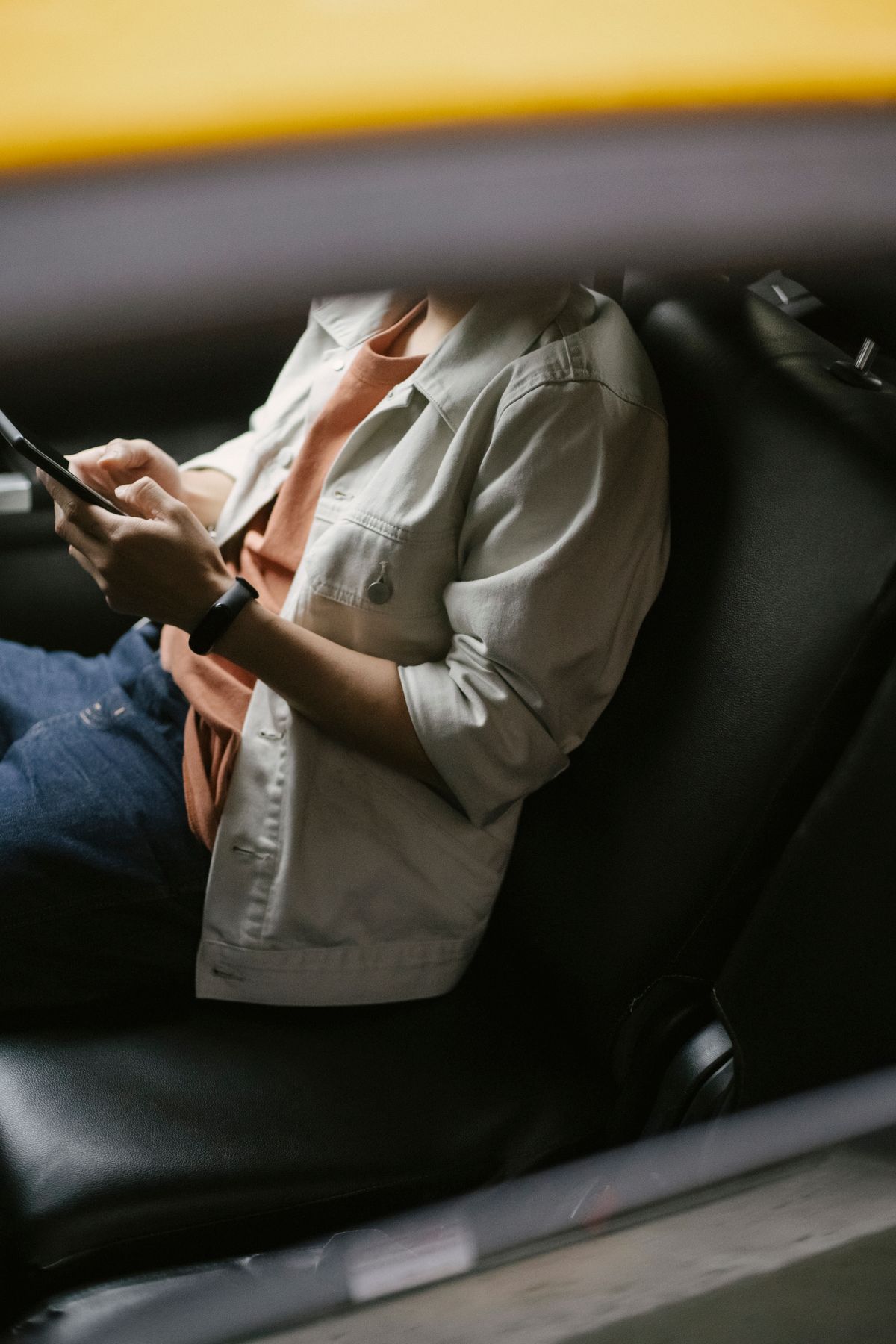 A passenger in the back seat of a car checking a fare on their smartphone