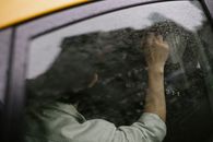 Unrecognizable man sitting on backseat of yellow cab on rainy day