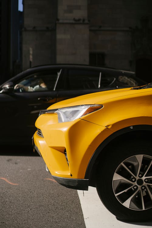 Yellow taxi car located on asphalt road on street in town in sunny day