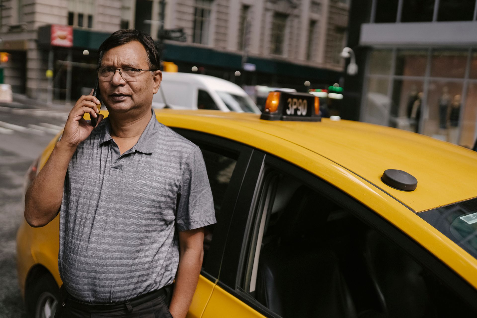 A confident taxi driver making a phone call in a bustling city street.