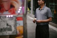 一位戴着眼镜的男性顾客在街边餐车前挑选农作物