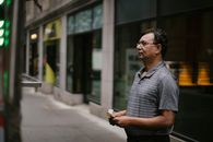 一名男子拿着现金，站在城市人行道上的餐车前，准备购买食物