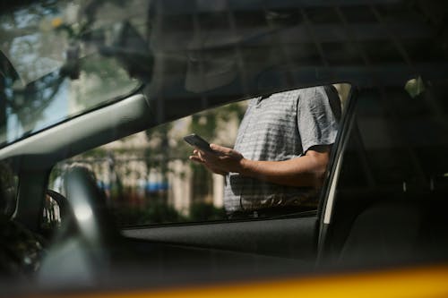 Gratis Orang Yang Menggunakan Smartphone Di Dekat Mobil Taksi Foto Stok
