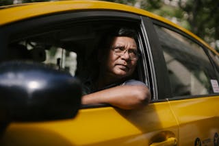 Serious ethnic male driver looking at opened window of taxi