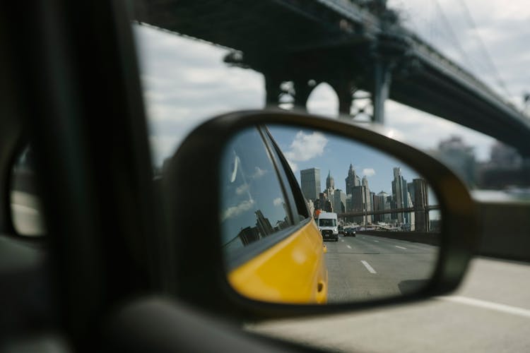 Reflection In Side Mirror Of Car Driving On Bridge