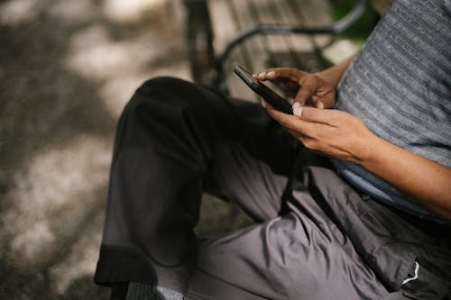 Gratis Orang Yang Menggunakan Ponsel Duduk Di Bangku Foto Stok
