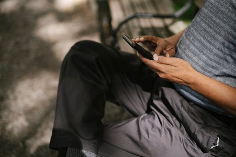 Person Using Phone Sitting On Bench