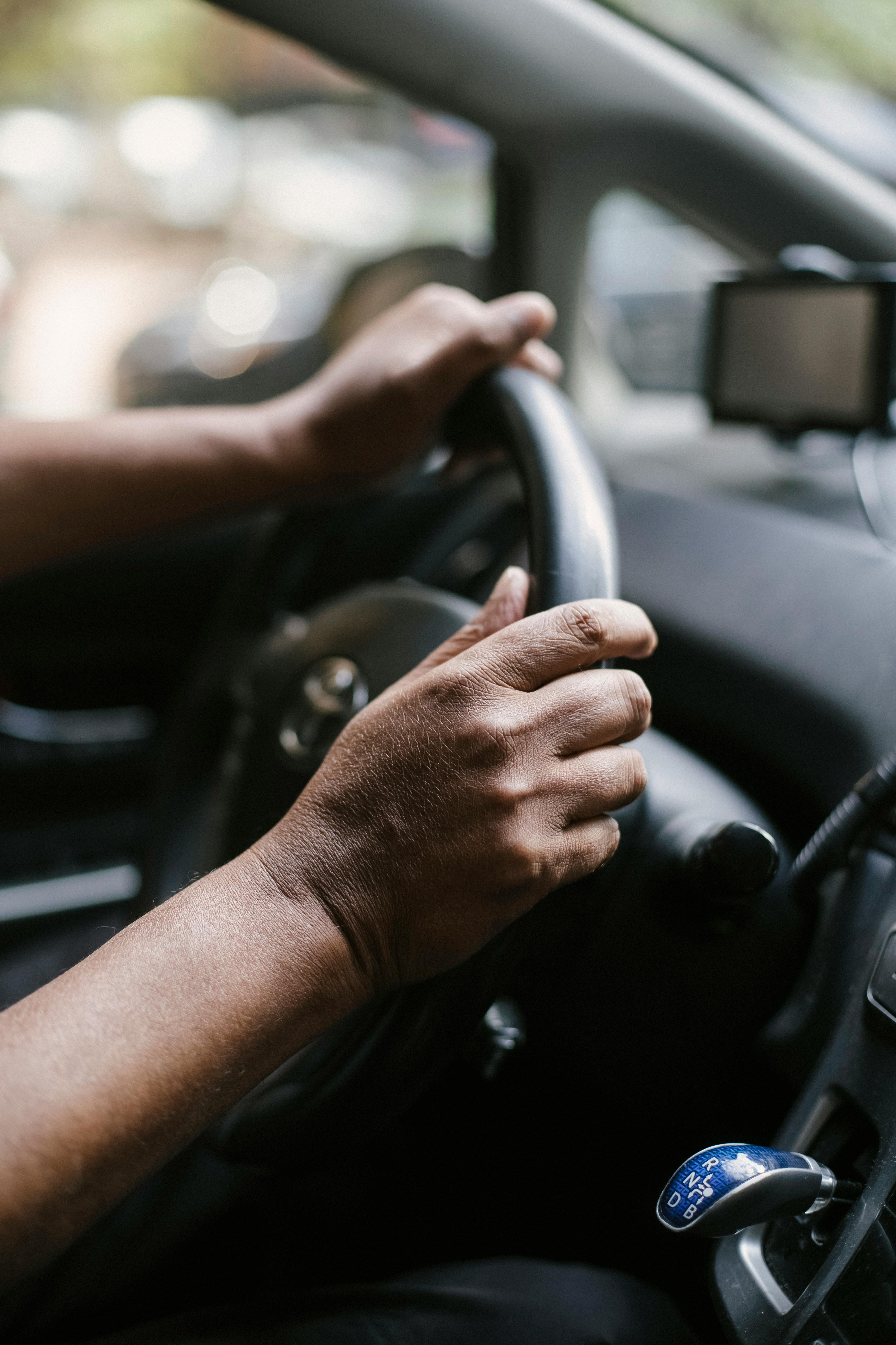 person holding steering wheel of car