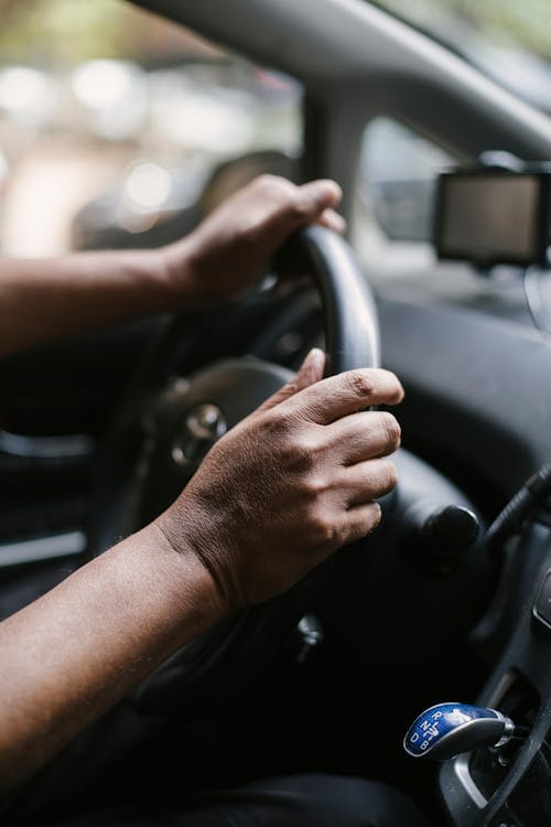 Person holding steering wheel of car