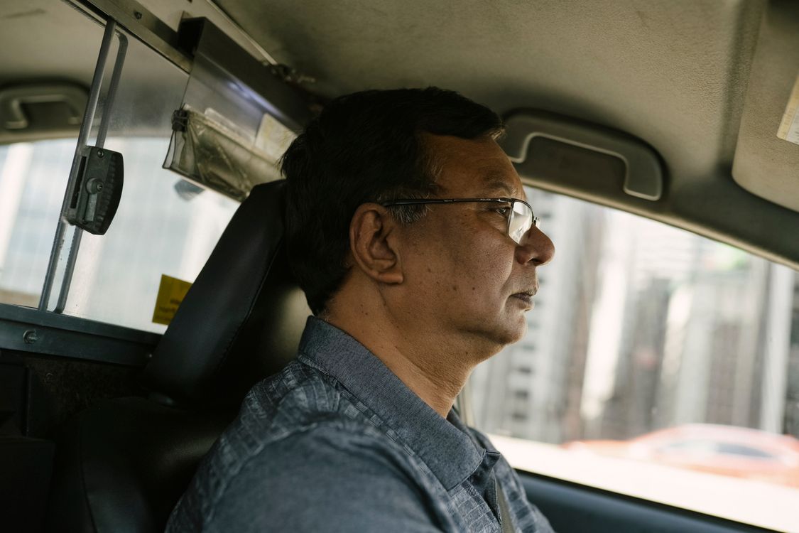 Taxi indépendant au volant – garanties assurance professionnelle Chauffeur de taxi indépendant concentré au volant de son véhicule en ville