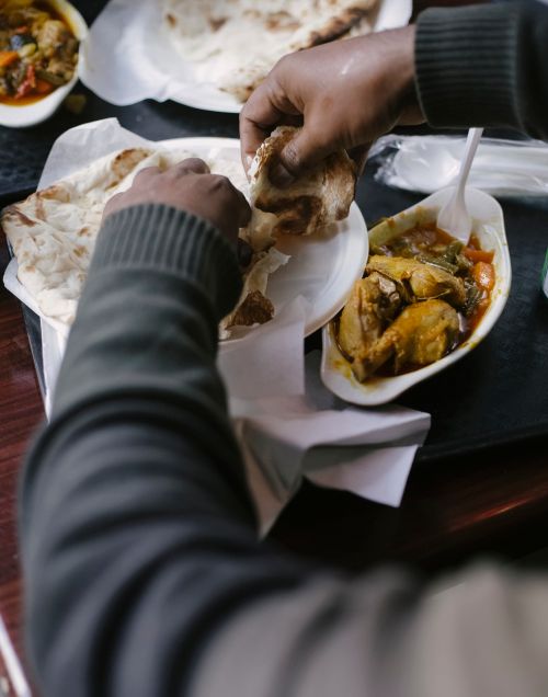 Free Crop unrecognizable person in casual clothes eating meat and pita while having dinner in cafe Stock Photo