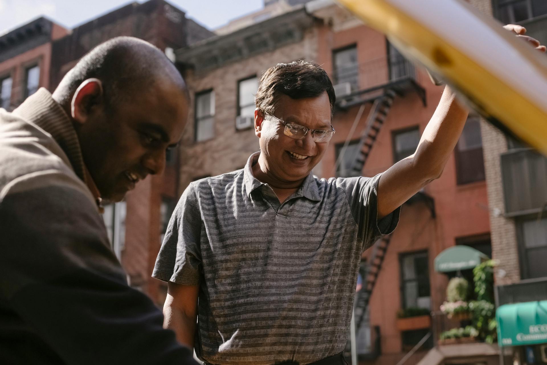 Cheerful ethnic man repairing broken car with friend