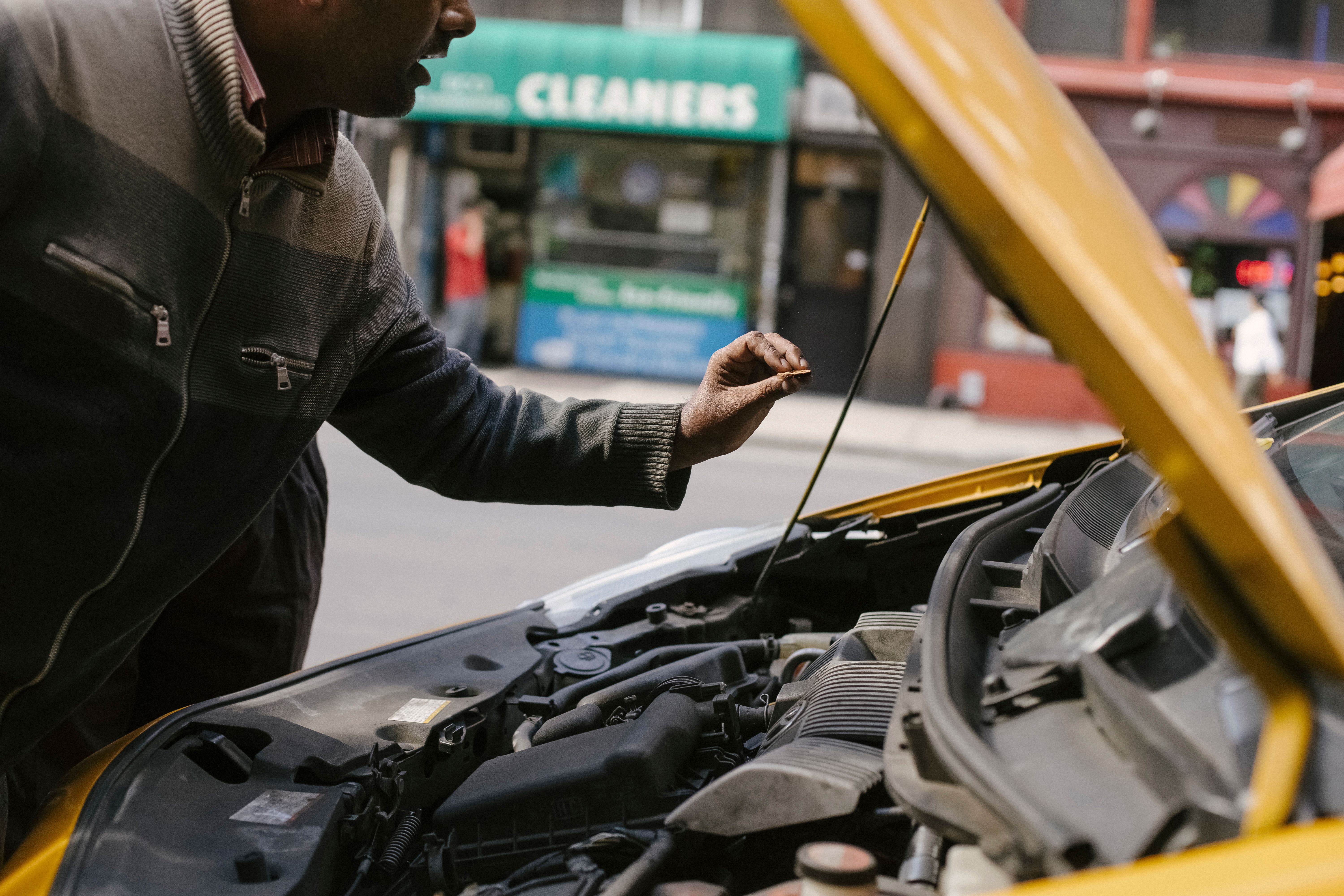 Man checking under his car hood